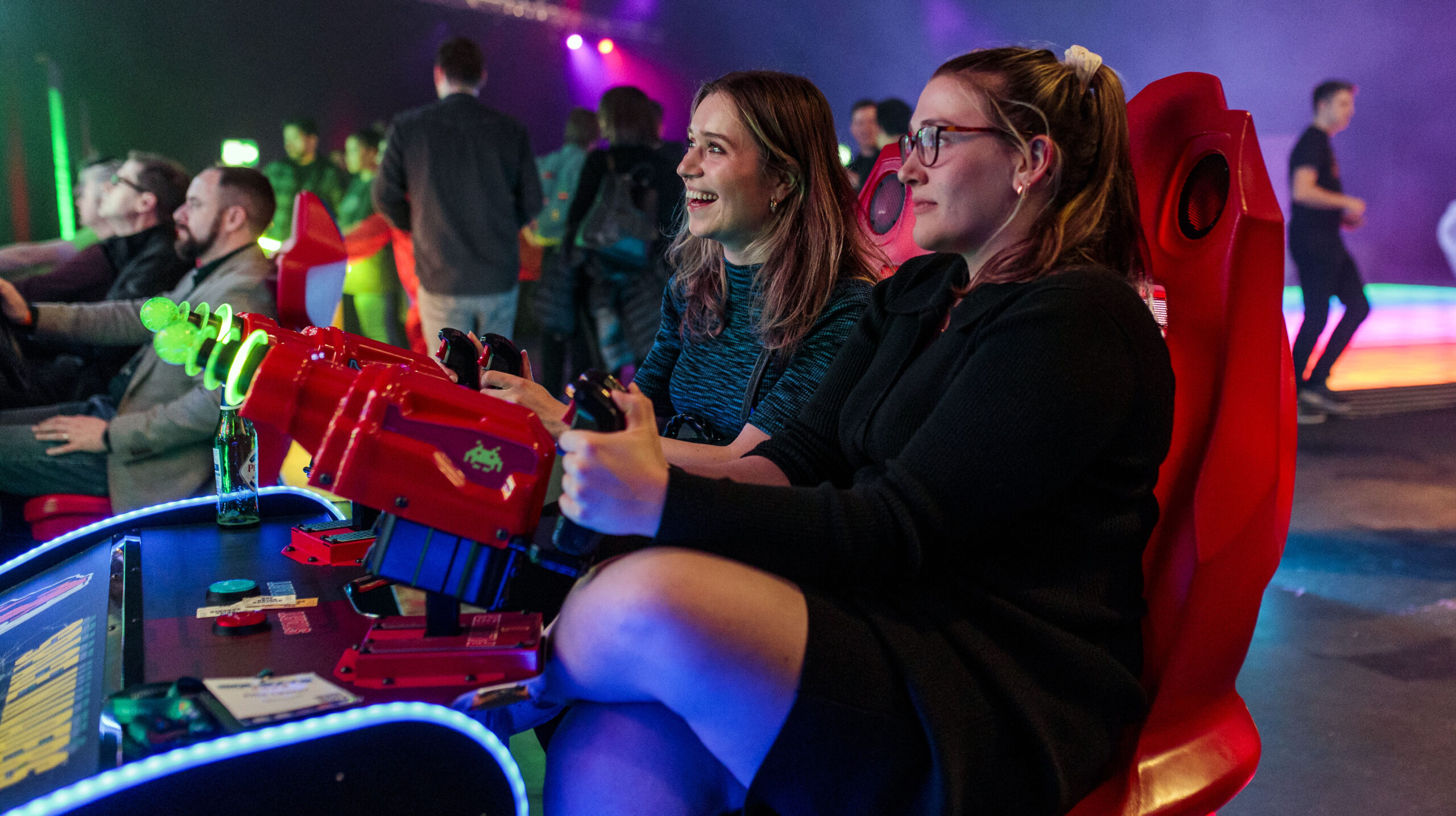 Two people playing on an electronic game at SQLBits 2022, arcade themed data conference.