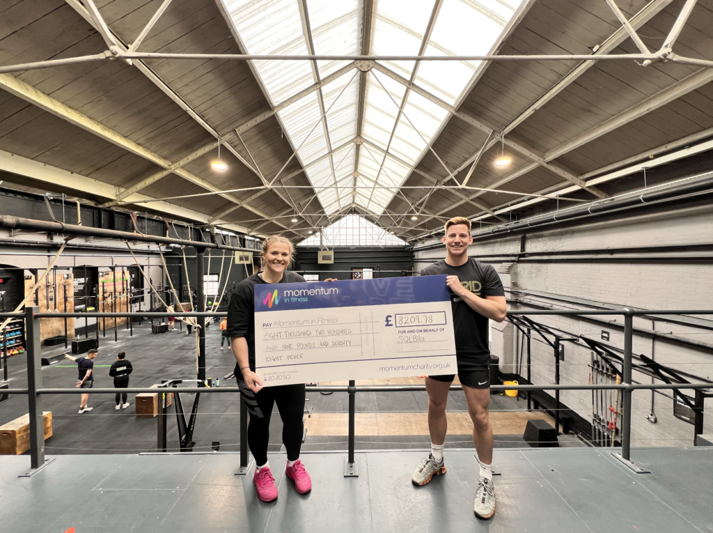 Two members of the Momentum team holding a cheque from SQLBits 2024